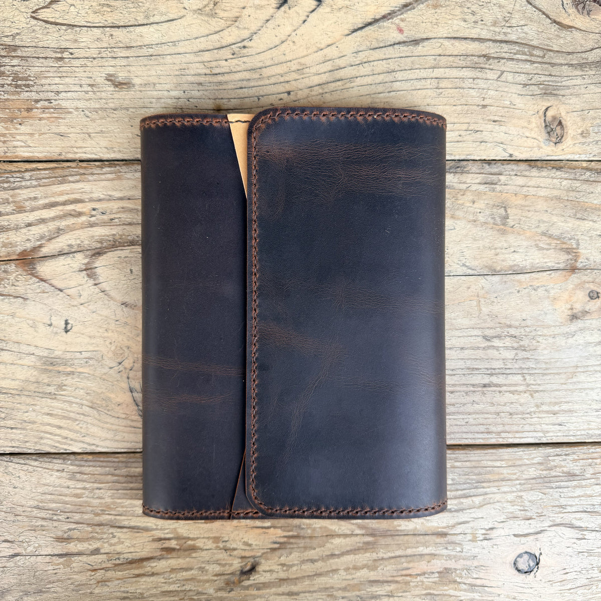 A dark brown leather cover or notebook cover with visible stitching. 