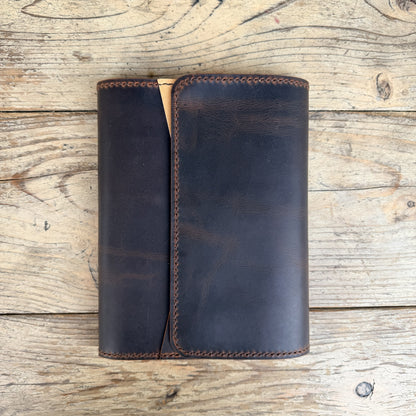 A dark brown leather cover or notebook cover with visible stitching. 
